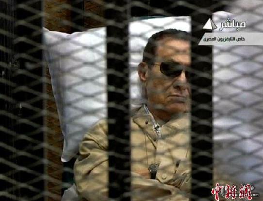 资料图：2012年6月2日，埃及法院对前总统穆巴拉克被控下令武力镇压示威者案做出判决。大法官艾哈迈德·里法特Ahmed Rifaat宣布，穆巴拉克被判终身监禁。图为穆巴拉克在庭审现场。（视频截图） 