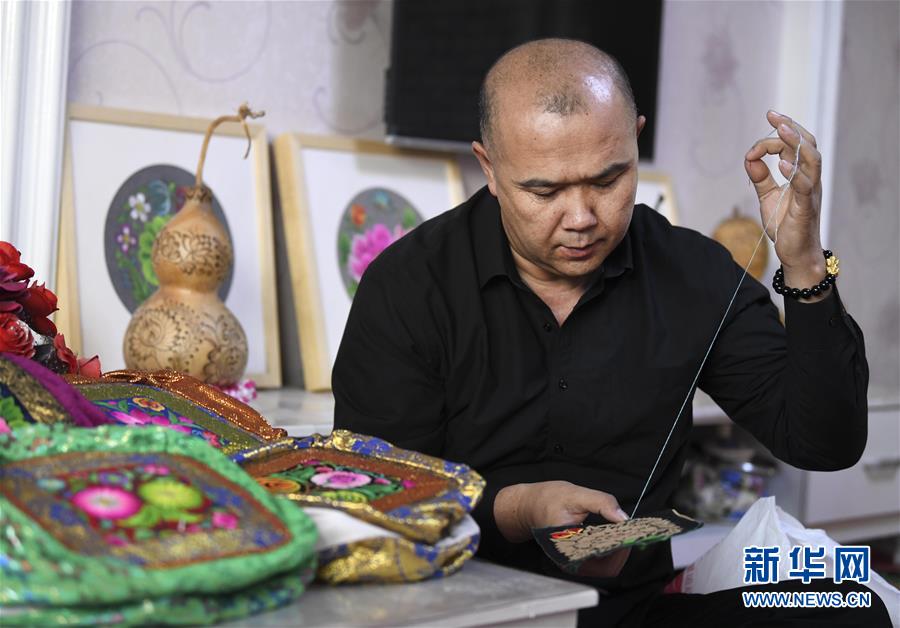 在新疆哈密市，刺绣艺人卡德尔·热合曼在制作绣品（2019年3月8日摄）。 